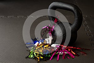 Black kettlebell on a black gym floor with blue, green, red, pink and gold noisemakers photo